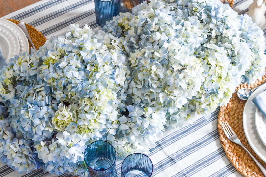 Blue and cream hydrangea blooms arranged down the centre of a dinner table.