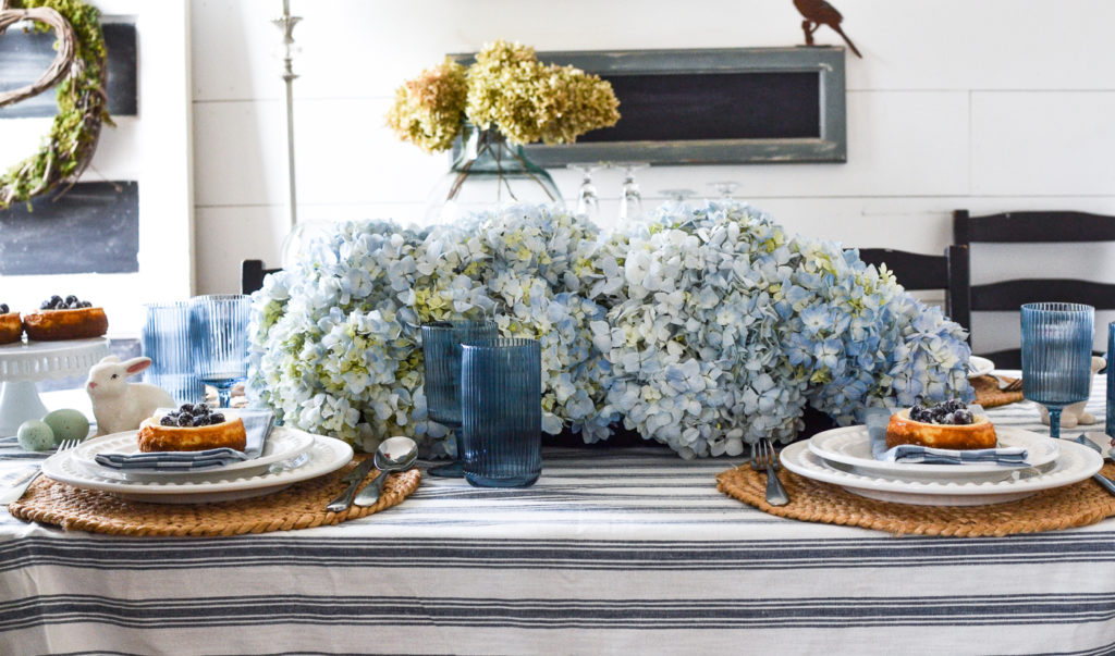 A blue and white tablescape set for spring with a large hydrangea centrepiece.
