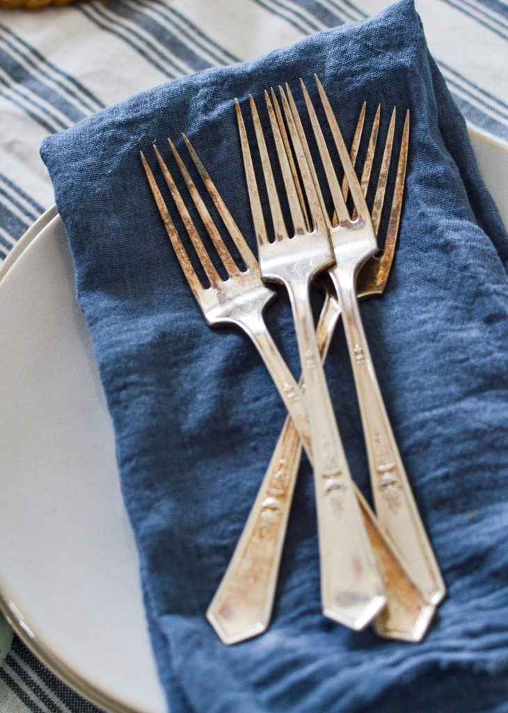 4 Antique silver dessert forks on top of a blue napkin