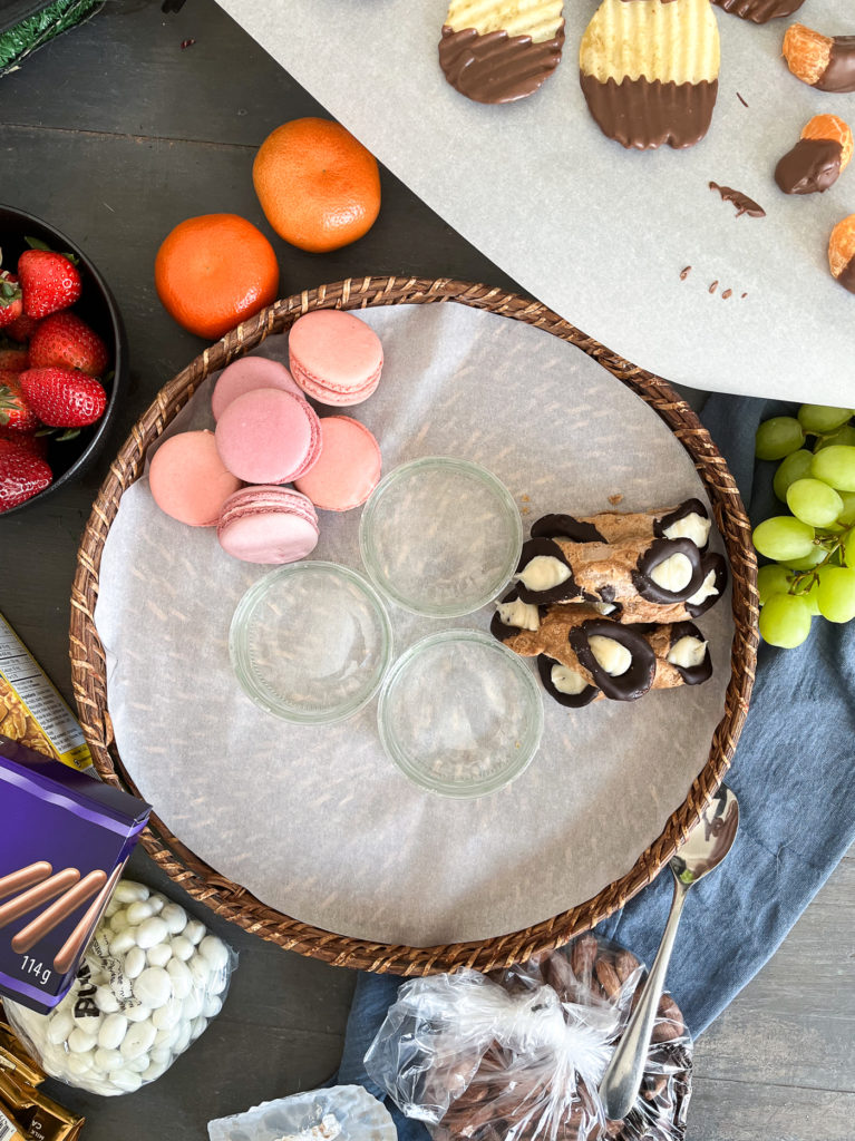 Begin arranging dessert board by placing larger desserts like these macarons and cannolis first.