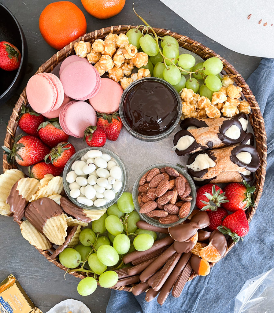 Overhead view of dessert board filled with fresh fruit, cookies, chocolate dip and nuts.