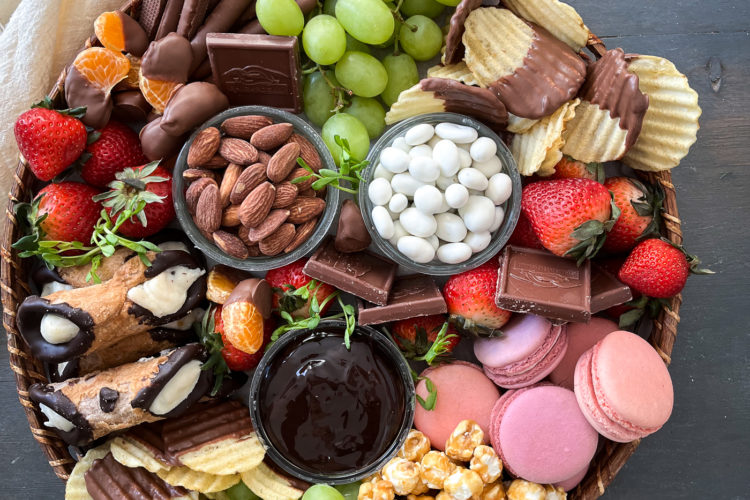 The ultimate dessert grazing board loaded with cookies, cannolis, caramel corn, chocolate dipped potato chips and fresh fruit.