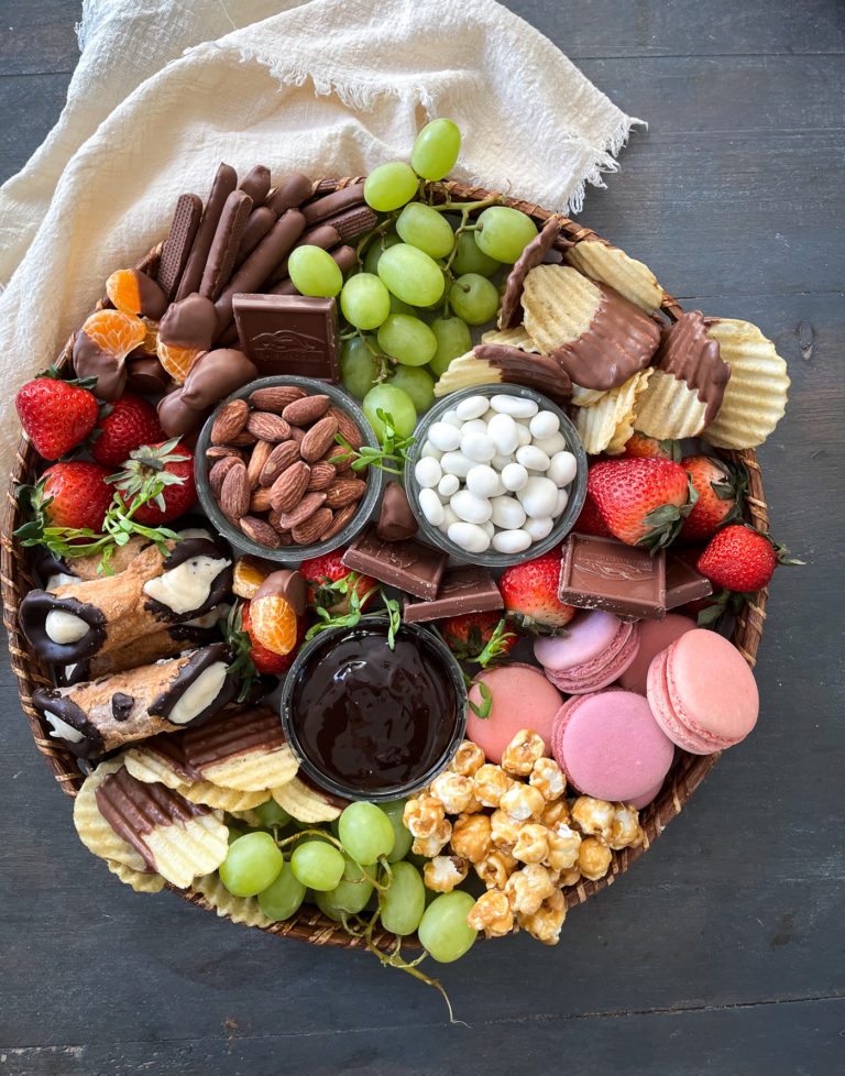 The ultimate dessert grazing board loaded with cookies, cannolis, caramel corn, chocolate dipped potato chips and fresh fruit.