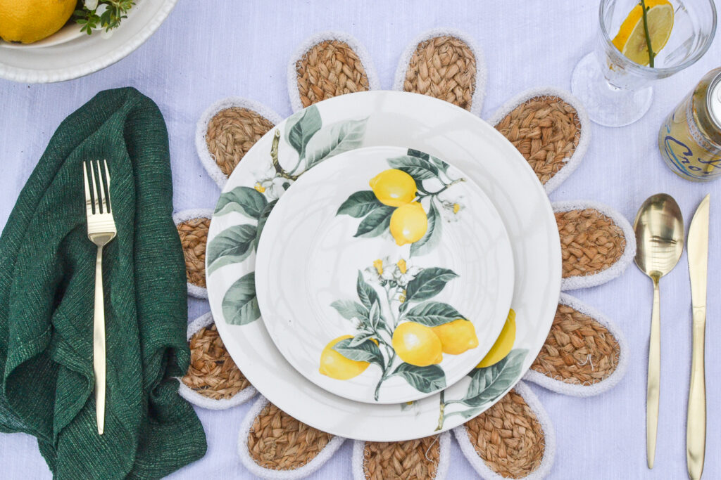 Lemon themed lunch and dinner plates stacked on a daisy shaped rattan place mat.