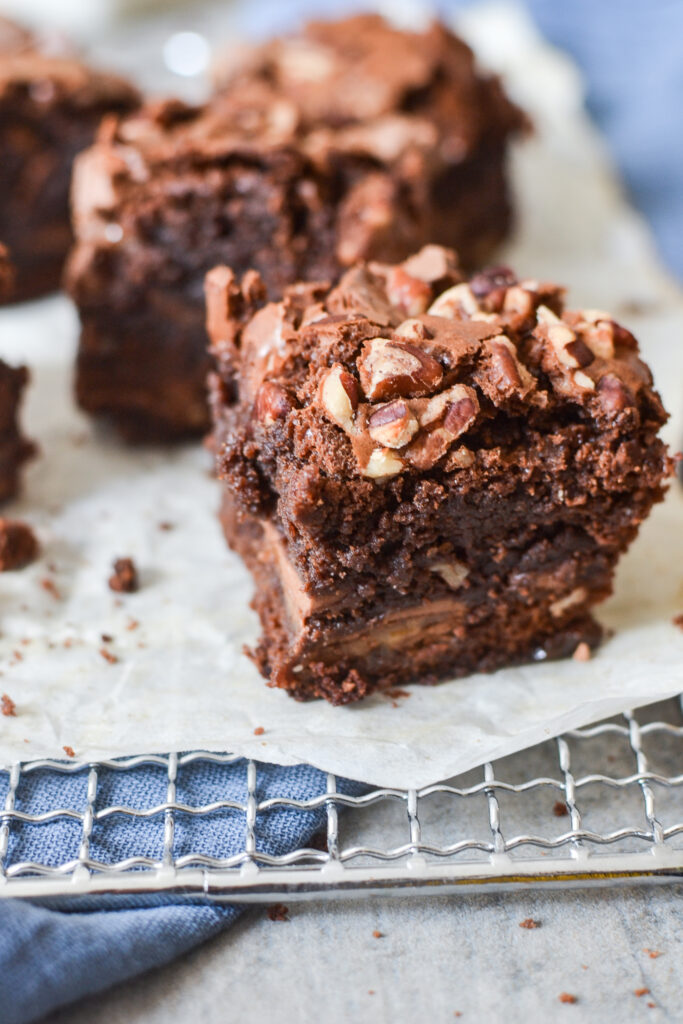 triple chocolate brownie with pecans on top on a sheet of parchment