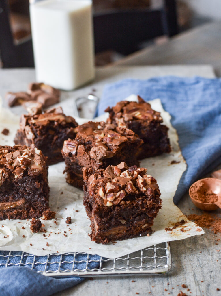 Squares of chocolate brownies arranged on a blue napkin and parchment paper