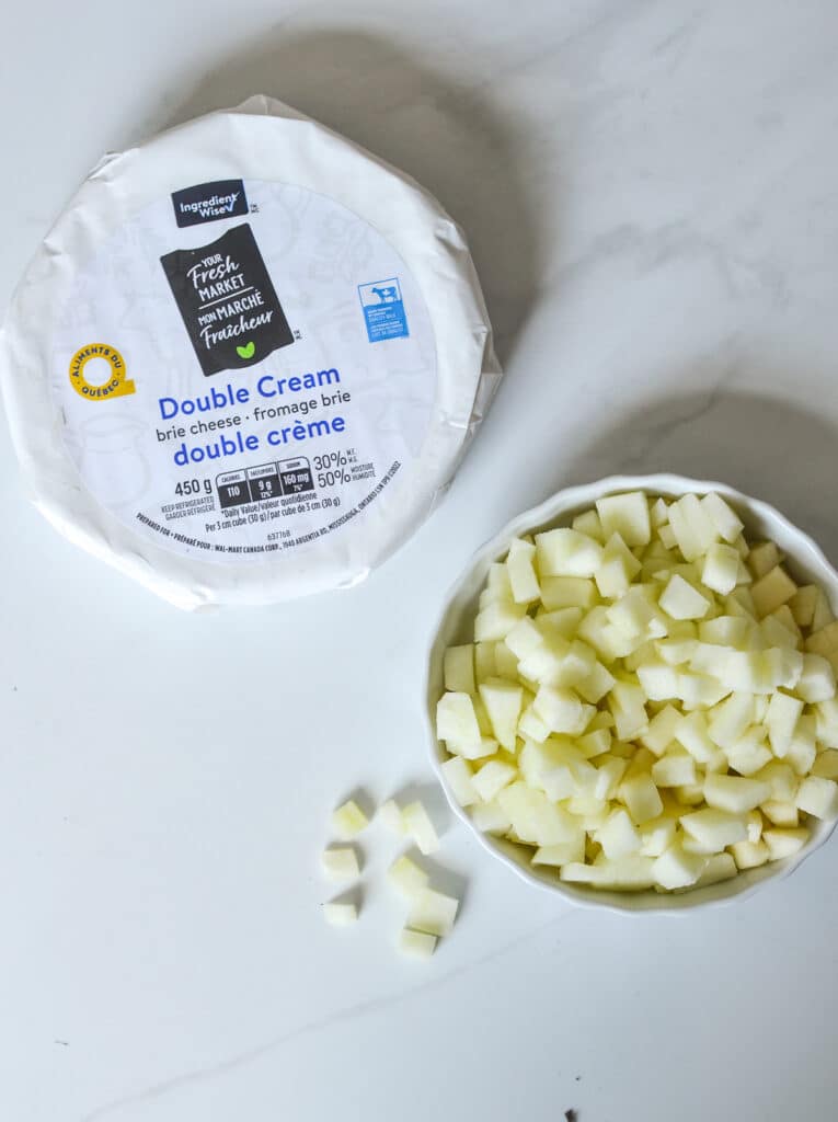 wheel of brie cheese and a bowl of chopped apples