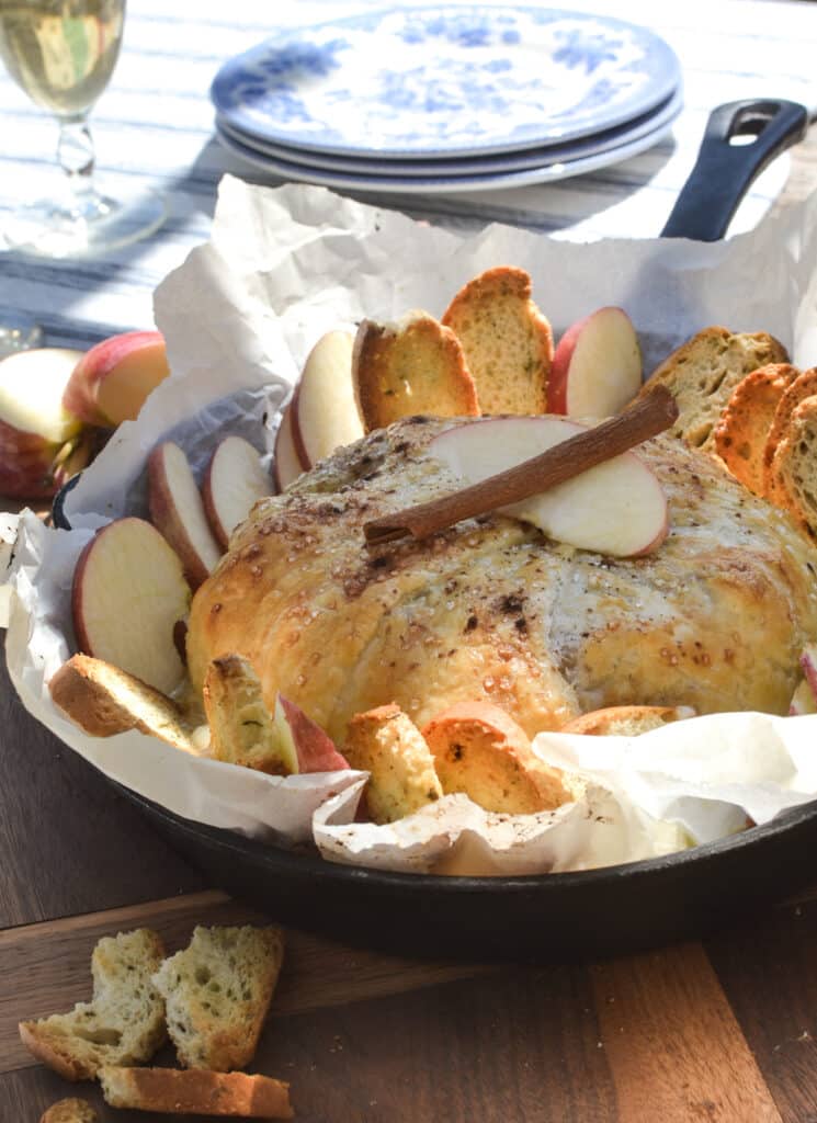 Puff pastry brie with apple and cinnamon in a cast iron frying pan lined with parchment paper.