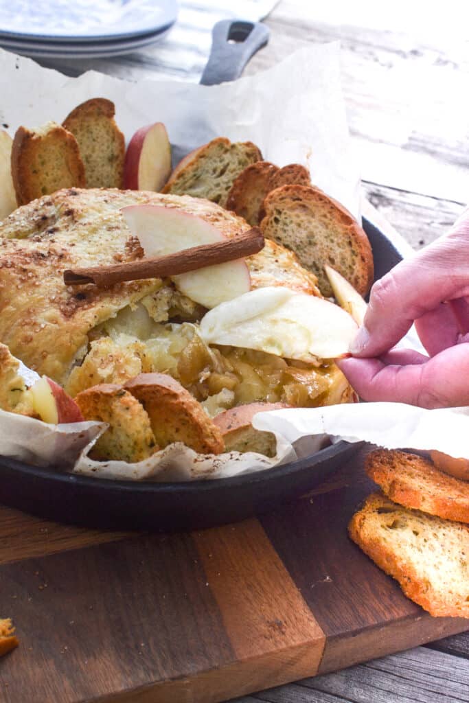 An apple slice dipped into melted brie in puff pastry.