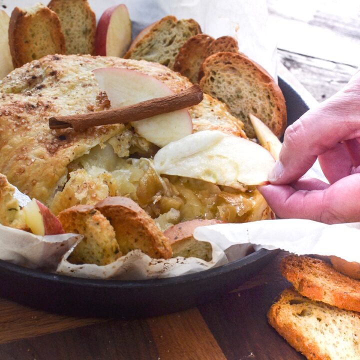 An apple slice dipped into melted brie in puff pastry.