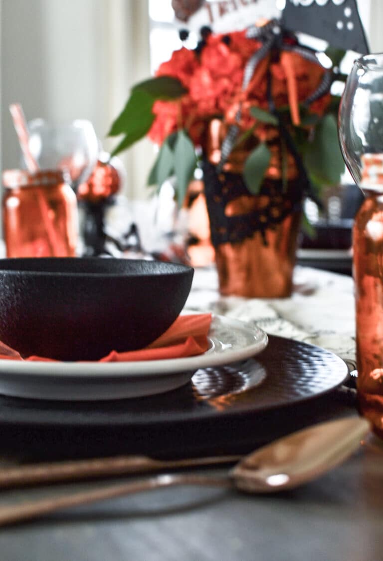 A close up of a black bowl stacked on a white plate and plate charger plate