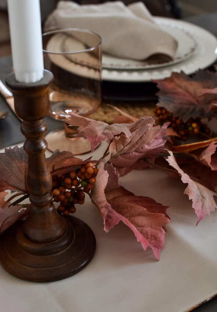 Wood candlestick beside a fall leaf garland.