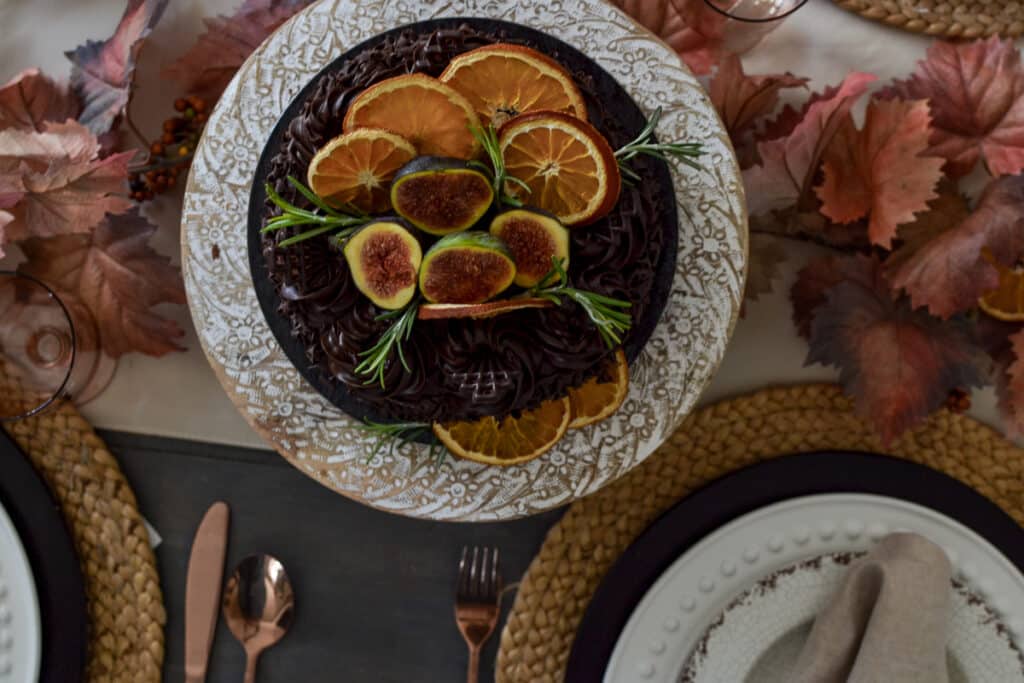 Overhead view of a chocolate cake decorated with dried oranges and sliced figs.