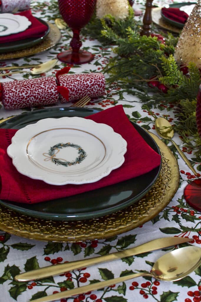 English Cottage Christmas table with gold flatware, green plates and red napkins.