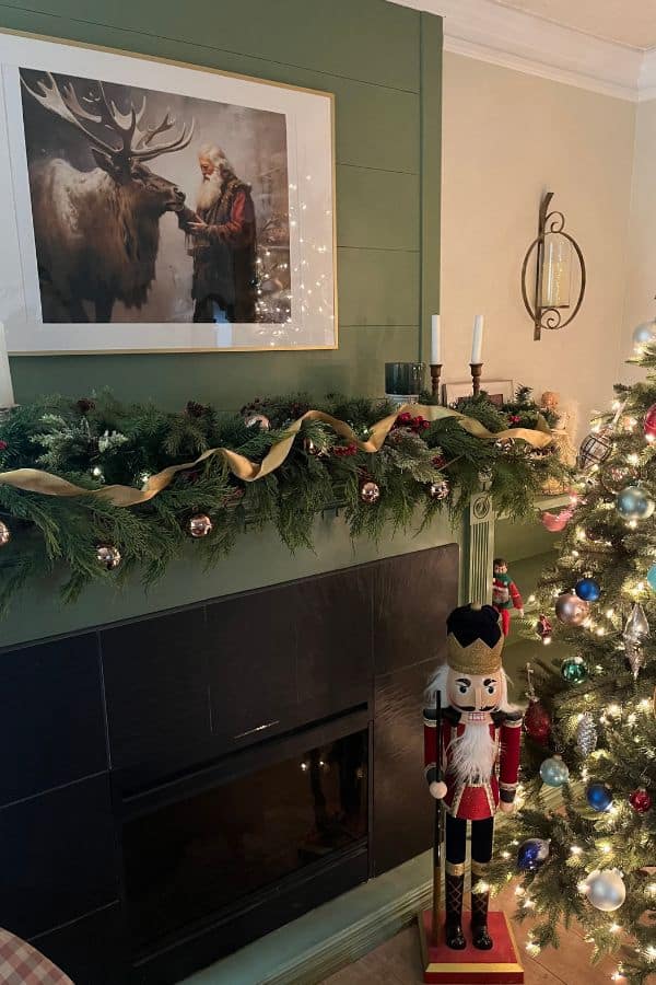 Fireplace mantel decorated with faux greenery and a nutcracker beside it.