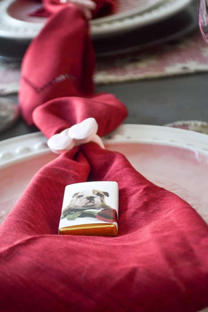 A red napkin with topped with a miniature chocolate bar with a picture of a bulldog puppy.