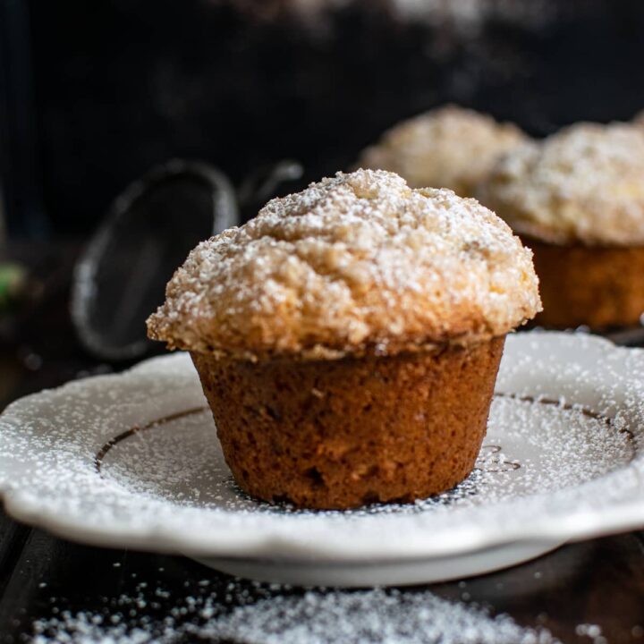 Banana muffin made with Greek yogurt on a white plate and sprinkled with confectioners sugar.