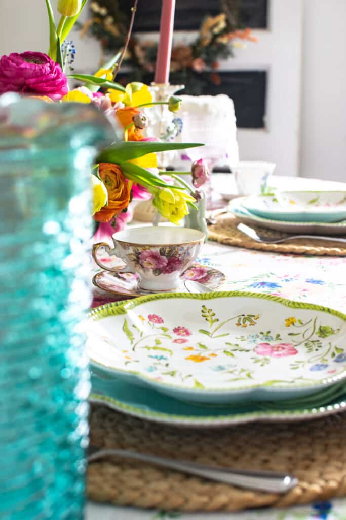 A spring fling themed tablescape decorated with floral print plates, tablecloth, and plaid napkins.