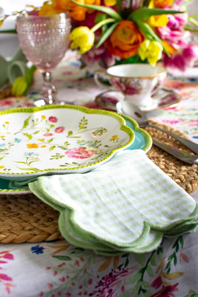 Spring table set with blue dinner plates topped with floral print salad plates and green check napkins
