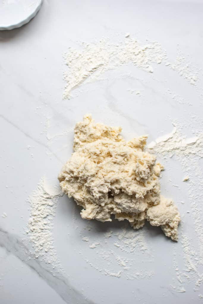 Rough dough for cinnamon rolls turned out onto a marble counter ready to be kneaded.