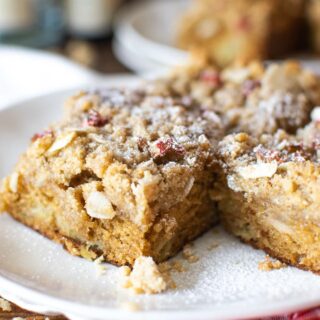 Rhubarb cake dusted with powdered sugar sitting on a white cake plate.