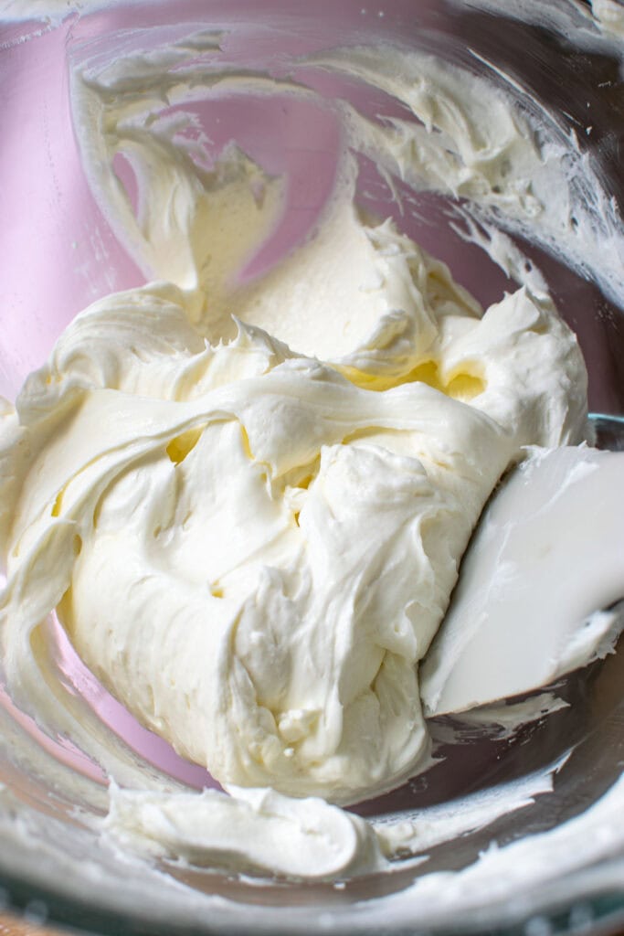 Cream cheese blended with whipped topping and confectioners sugar in a mixing bowl.