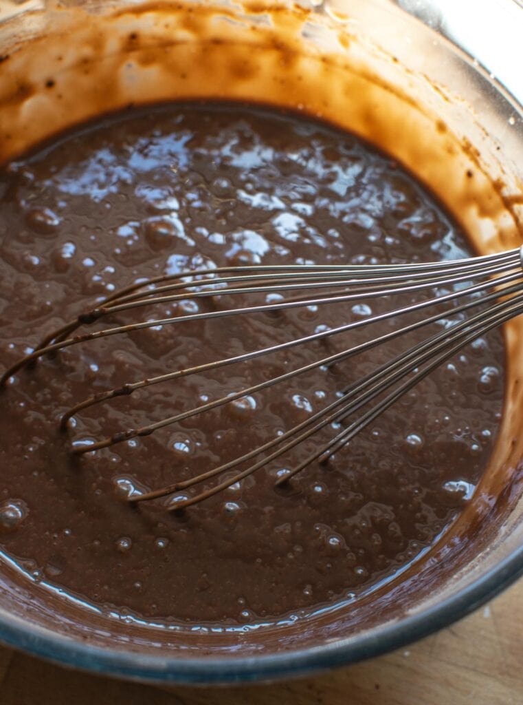 Instant chocolate pudding mix being whisked with milk until thick.