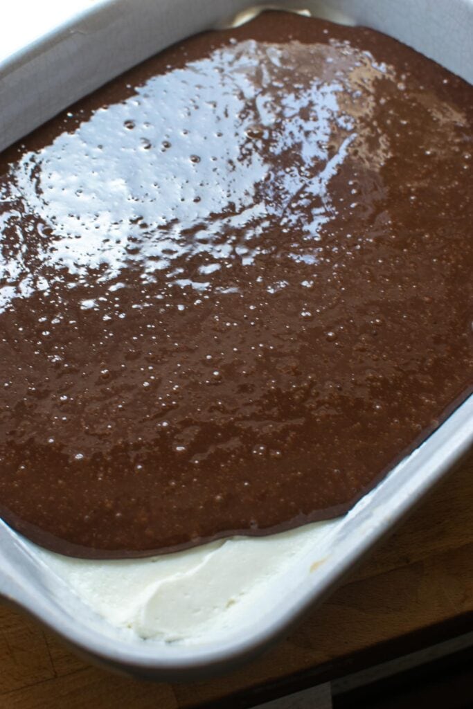 Chocolate pudding being spread over top of the cream cheese layer to make Chocolate Lush dessert.