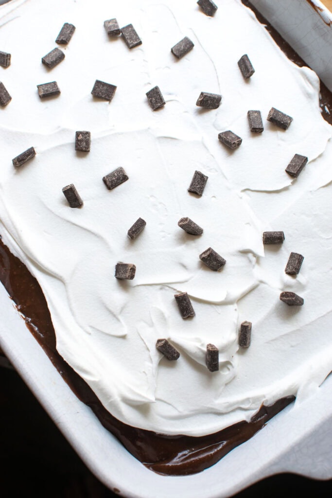 A layered chocolate pudding dessert topped with whipped topping and chocolate chunks.