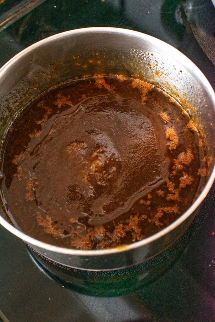 Ingredients to make a dressing for barbecue baked bean salad brought to a boil in a small saucepan.