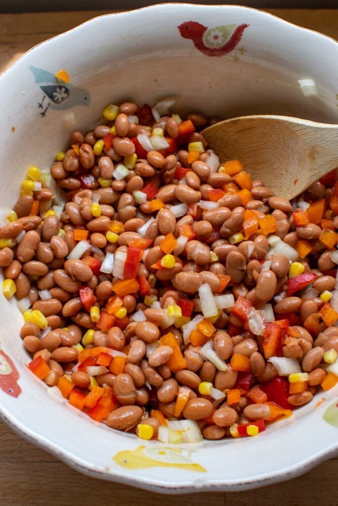 Pinto beans, bell pepper, onion and corn tossed together in a large serving bowl.
