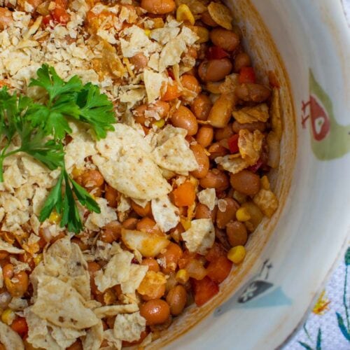 Baked bean salad topped with crushed tortilla chips and parsley.