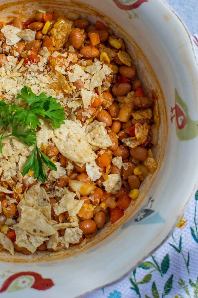 Baked bean salad topped with crushed tortilla chips and parsley.