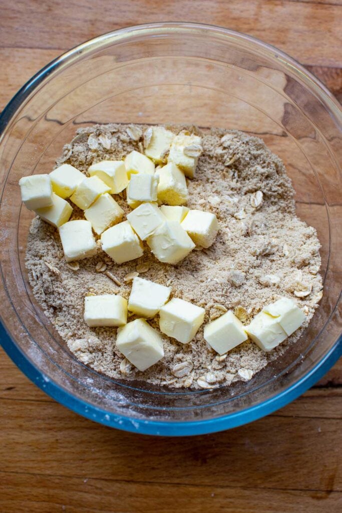 Chunks of cold butter added to the dry crumble ingredients before being mixed in.