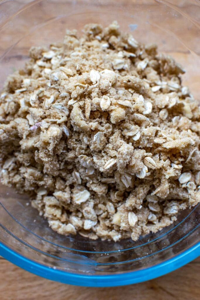 Crumble topping in a glass bowl ready to be sprinkled over fruit filling.