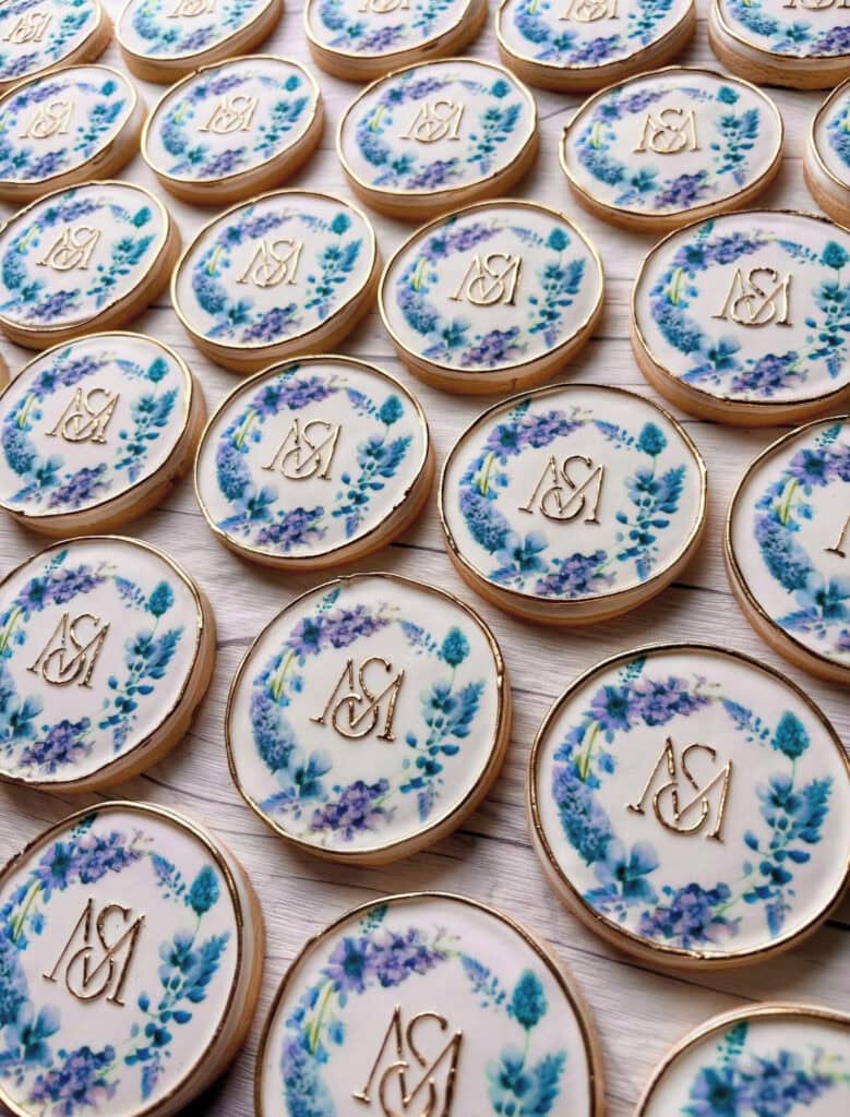 Custom monogrammed sugar cookies with gold ending and purple flowers.