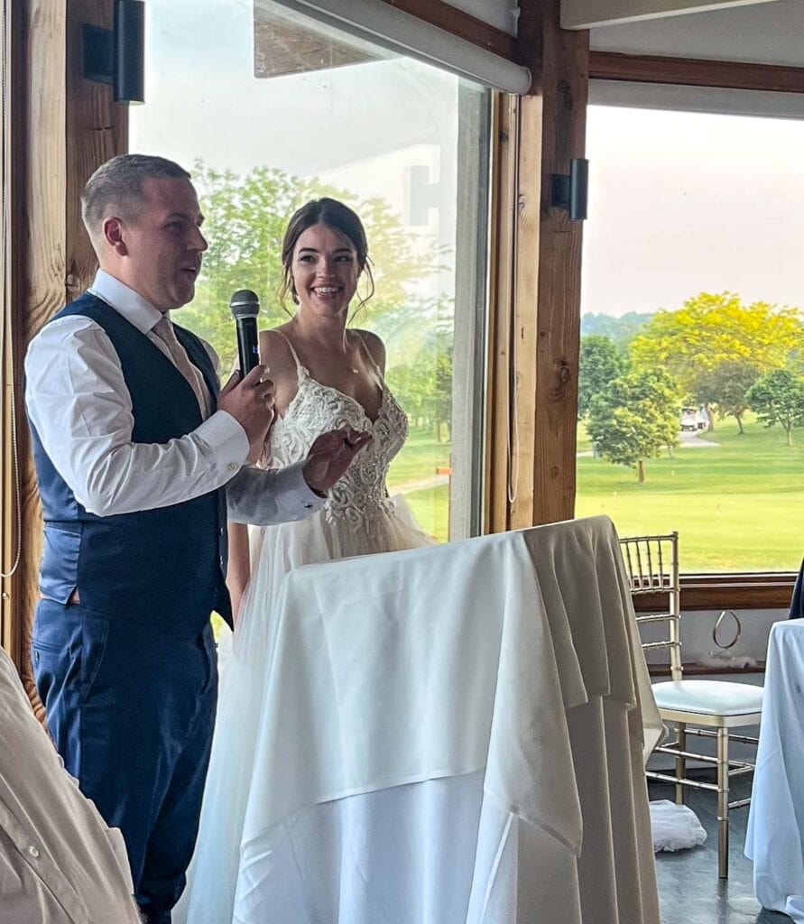 Bride and groom at a podium giving a thank you speech.