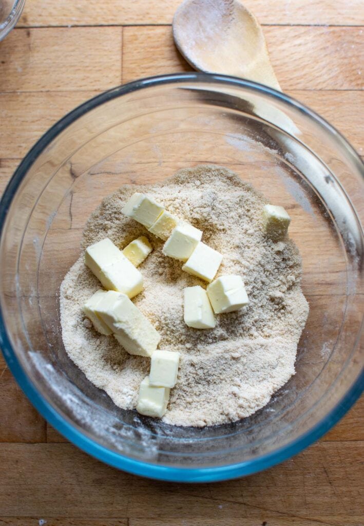 Cubes of butter added to flour and brown sugar before cutting it in to make crumble topping.