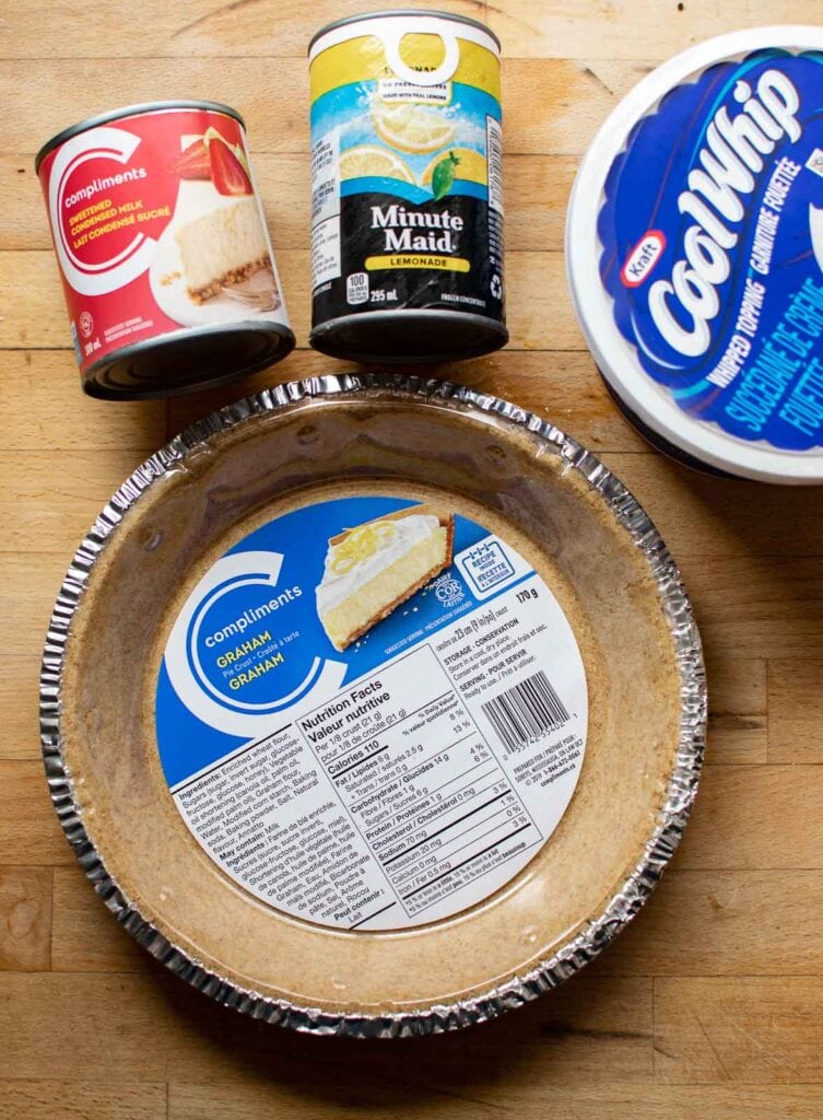 Ingredients to make an easy lemonade pie including frozen lemonade, sweetened condensed milk, Cool Whip, and graham pie crust.