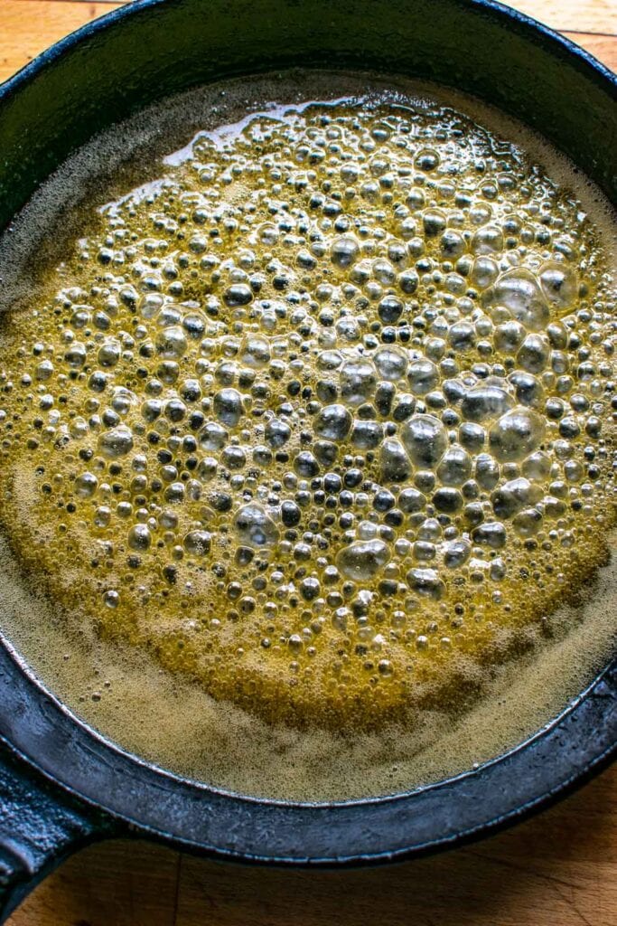 Butter and maple syrup simmering in a cast iron frying pan.