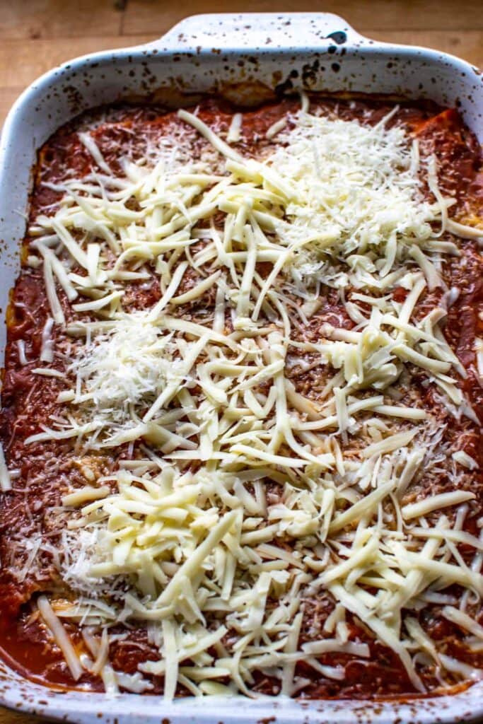 Shredded mozzarella and parmesan cheese on top of cooked manicotti noodles before melting in the oven.