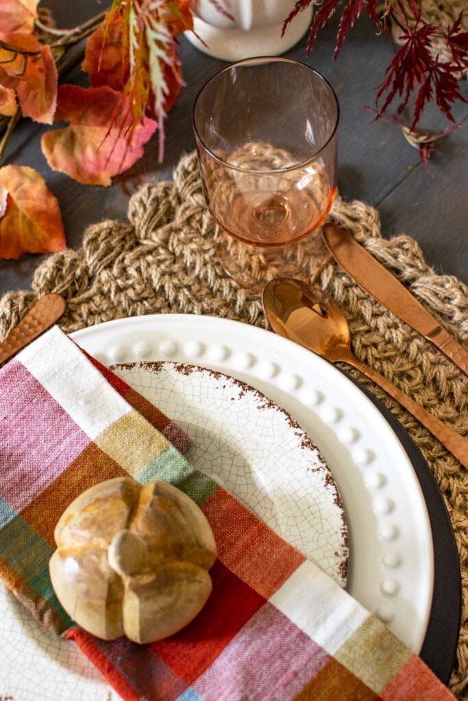 The corner of a place setting on a cozy fall dinner table.