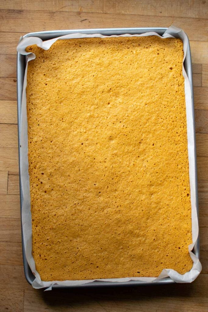 Pumpkin sponge cake fresh out of the oven and still in the parchment lined pan.