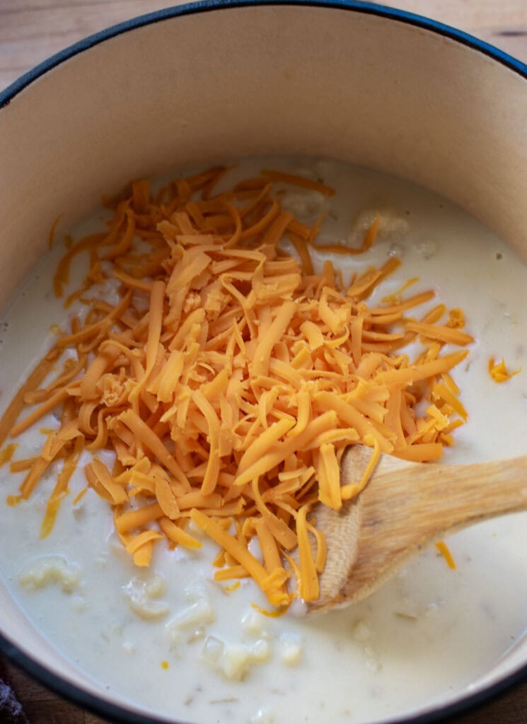 Cheddar cheese added to thickened cauliflower mixture to make cauliflower cheese soup.