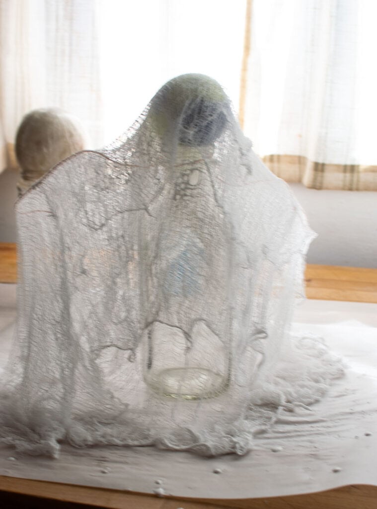 Cheesecloth soaked with liquid starch draped over a milk bottle to make a ghost.