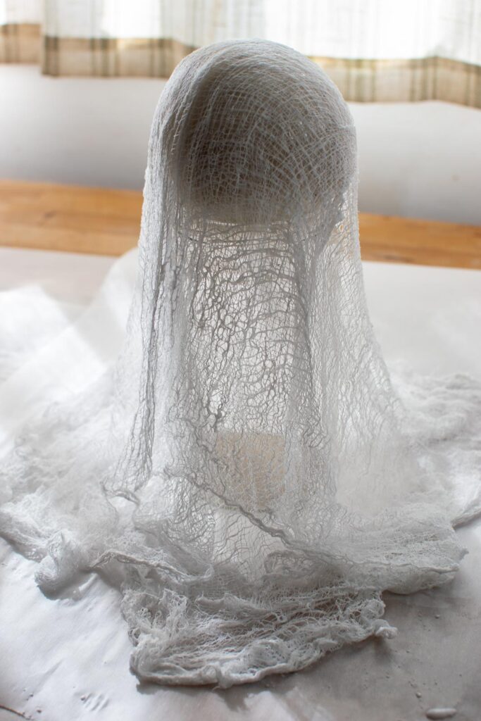 A smaller cheesecloth ghost made using a canning jar topped with a ball.