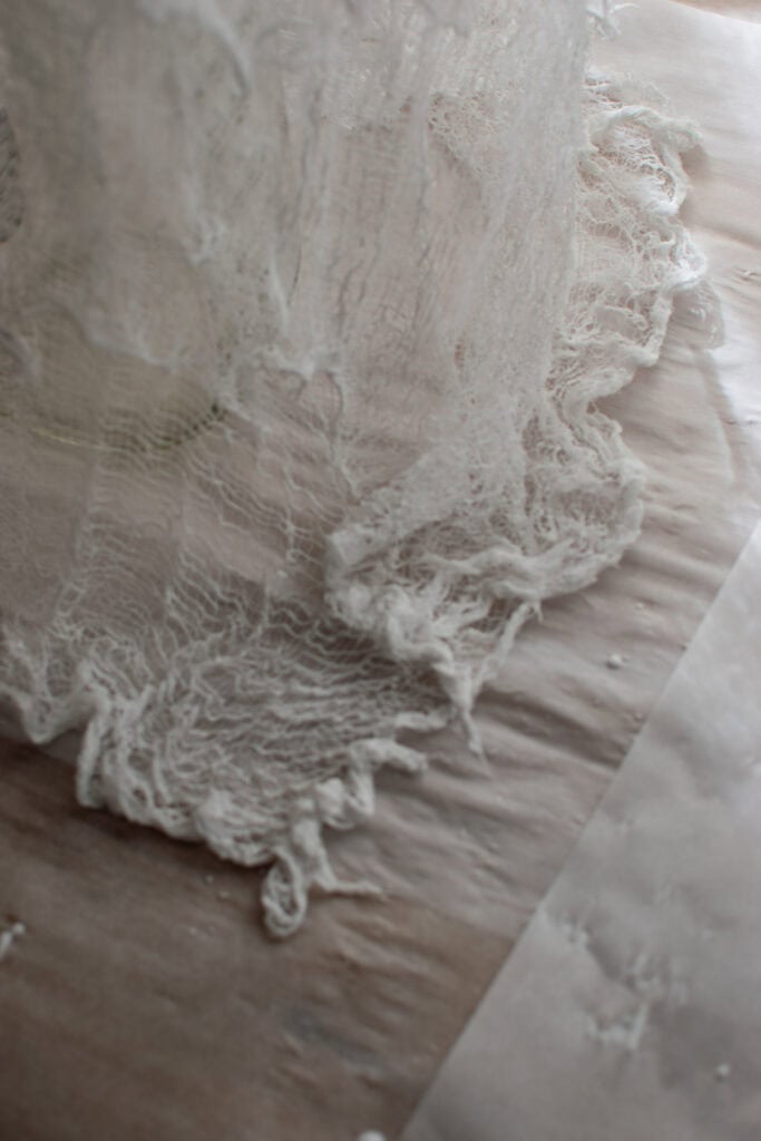 A close up of the bottom of the cheesecloth ghost show the fabric pooled around the bottom.
