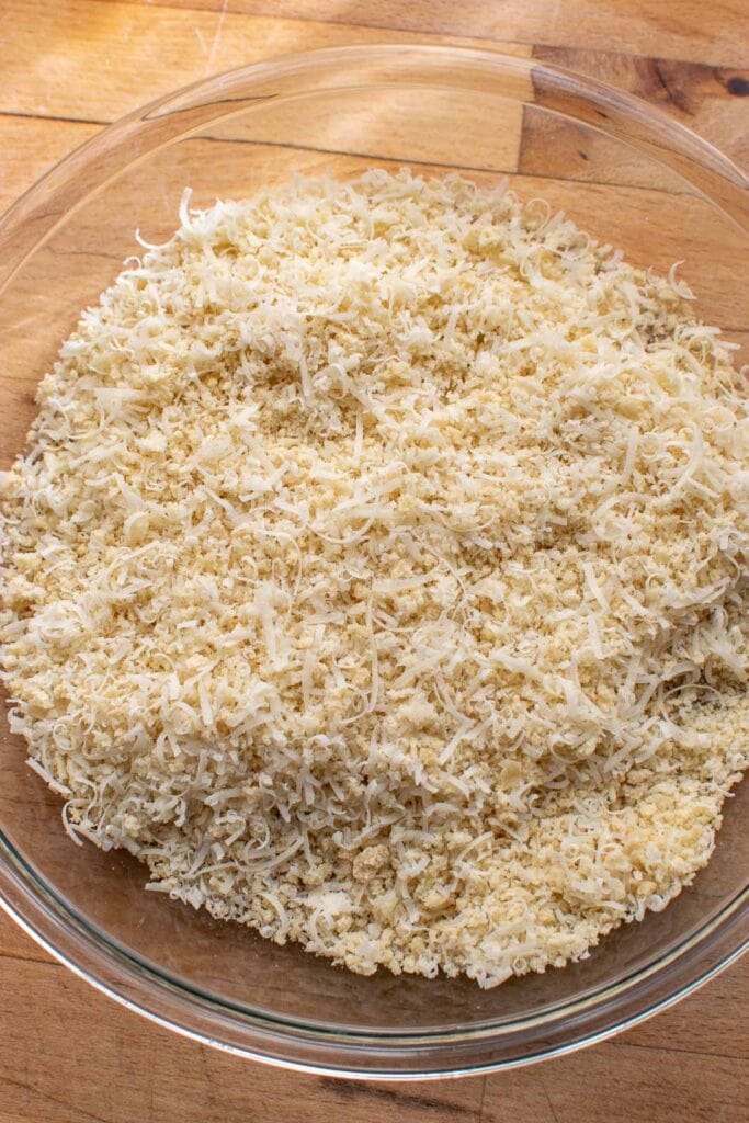 Panko bread crumbs and freshly grated parmesan cheese in a glass pie plate to coat chicken.