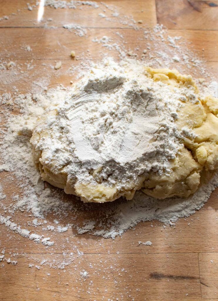 Shortbread cookie dough on a well floured counter with additional flour sprinkled on top to be kneaded into the dough.