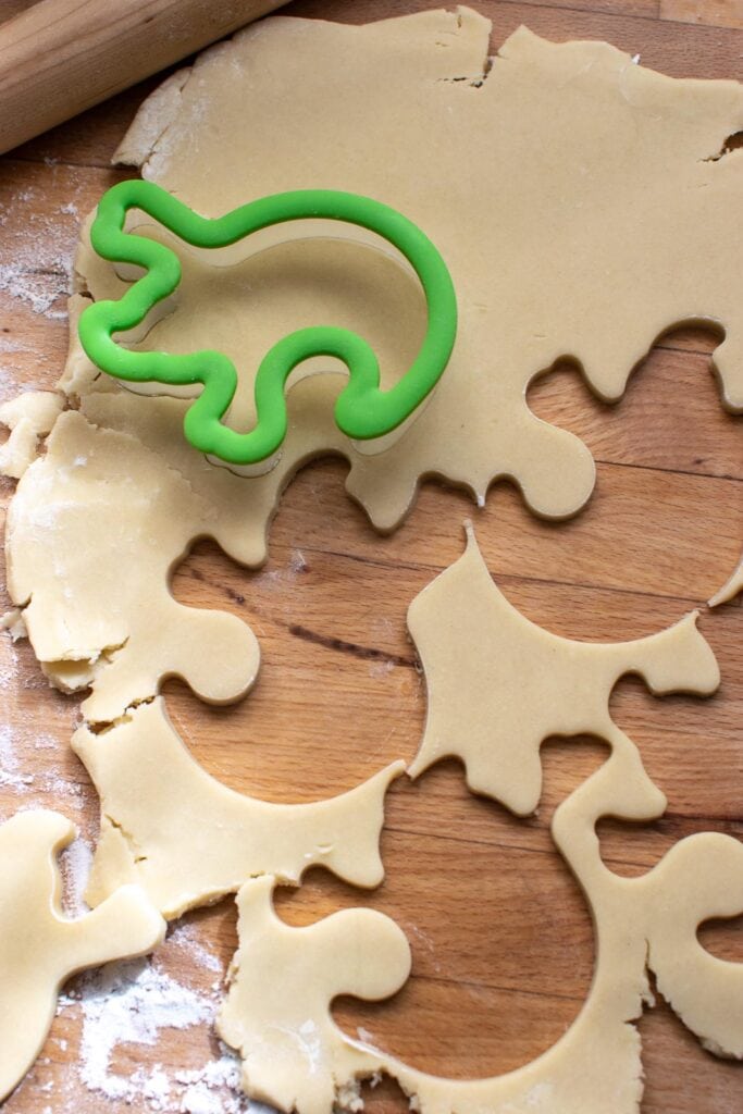 Shortbread cookie dough cut rolled out and cut into ghost shapes using a cookie cutter.